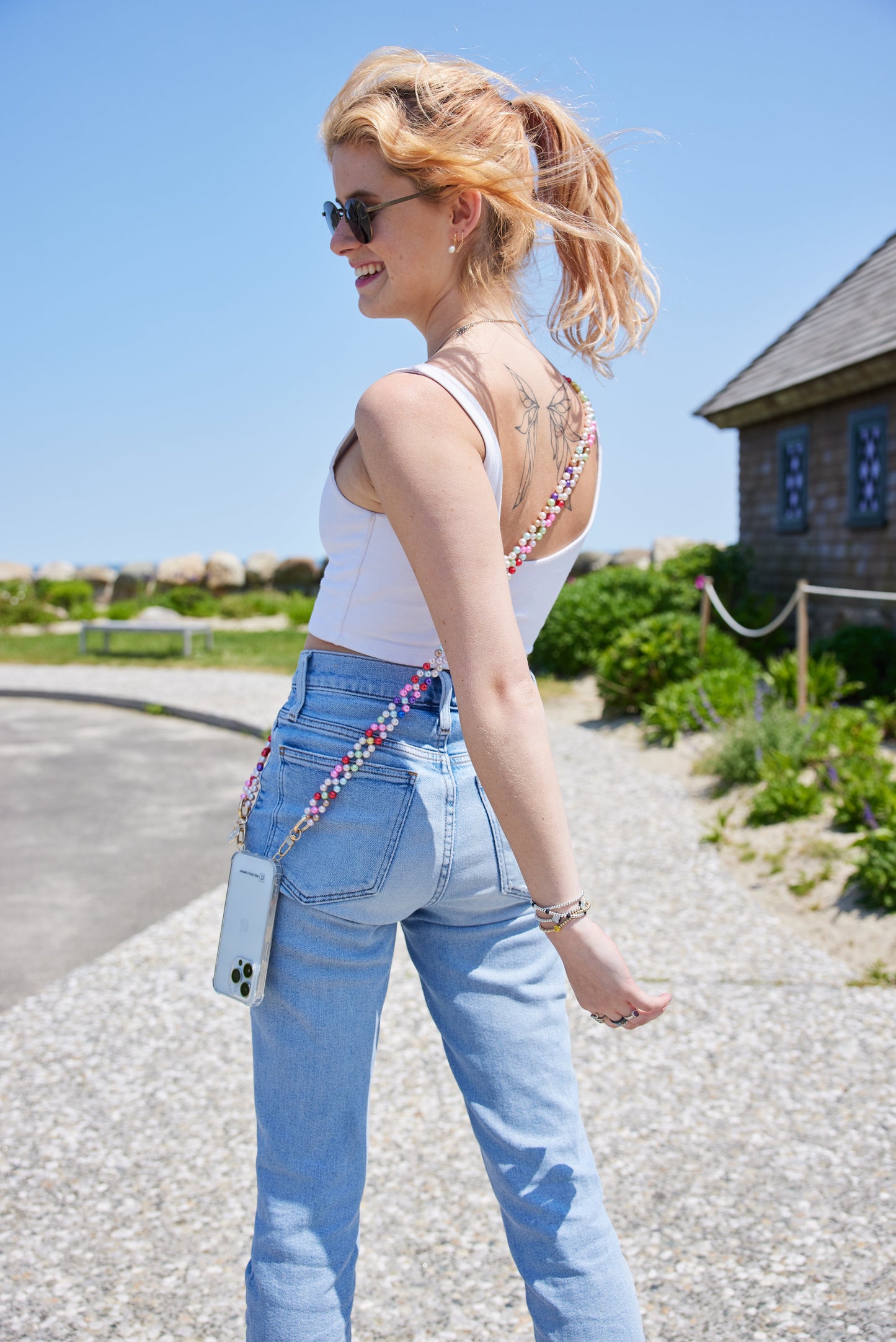 Detachable beaded phone chain in mixed colors worn with a phone, outdoor setting.