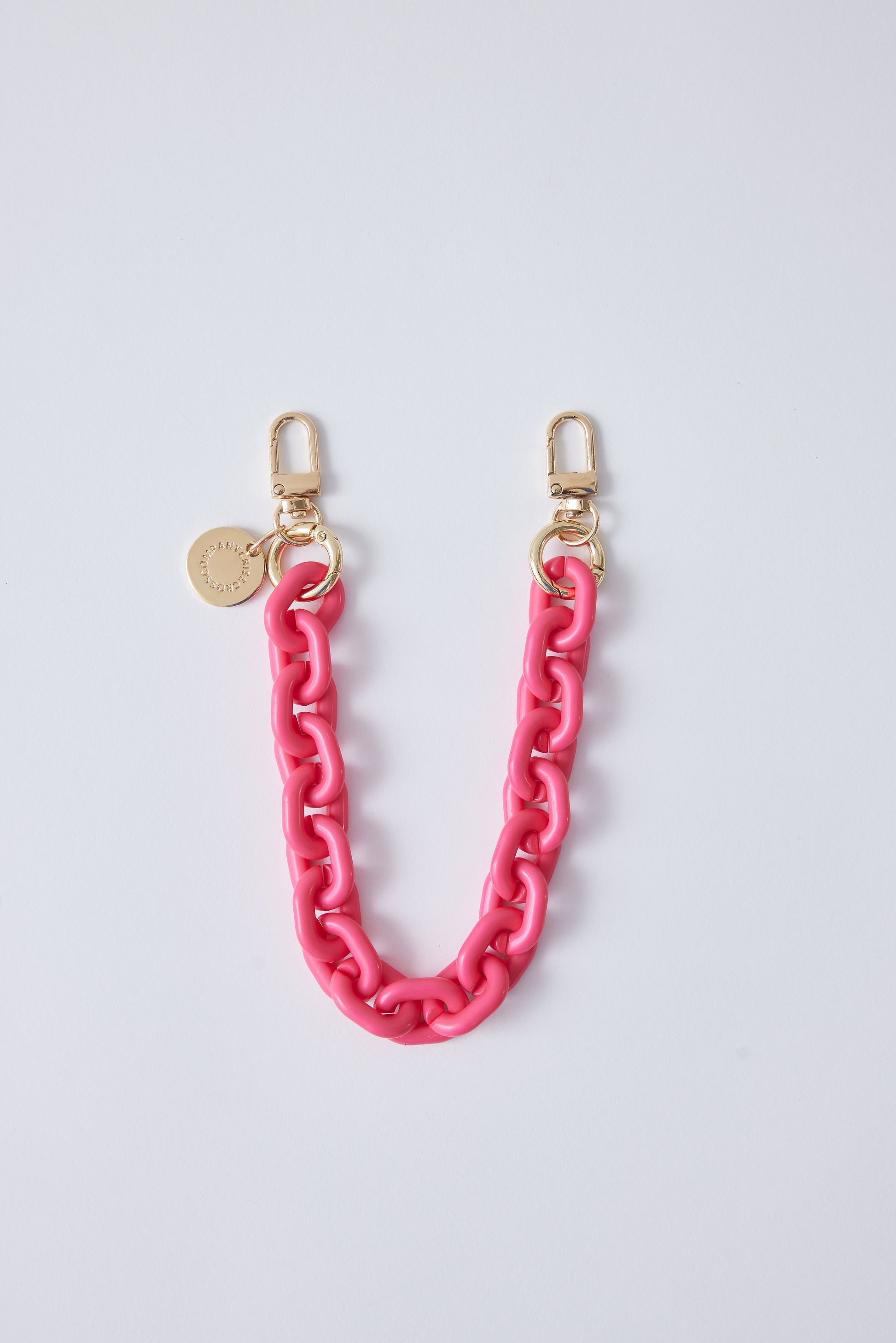 Detachable pink phone wristlet with gold clasps and charm.