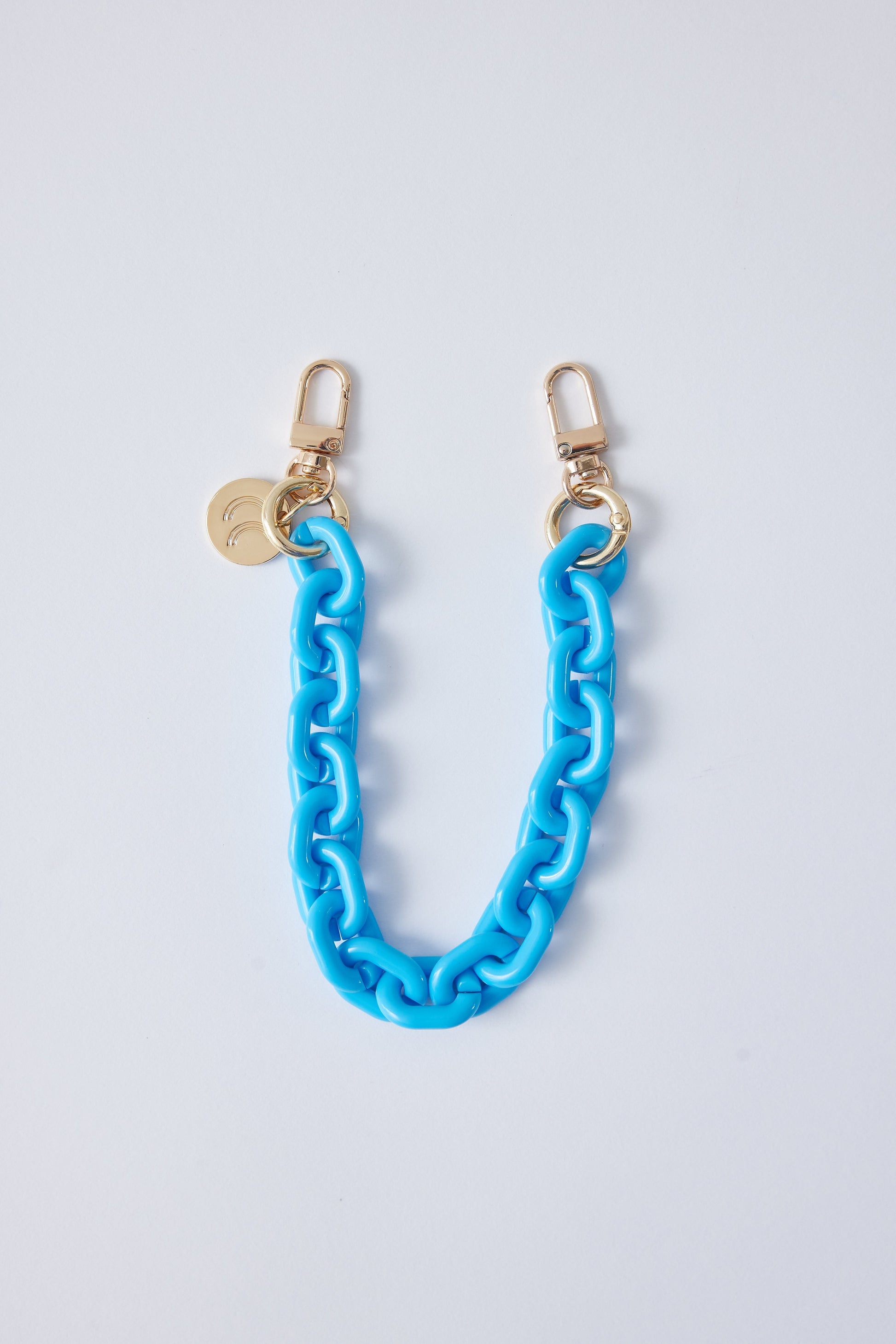 Detachable phone wristlet in blue with gold clasps.