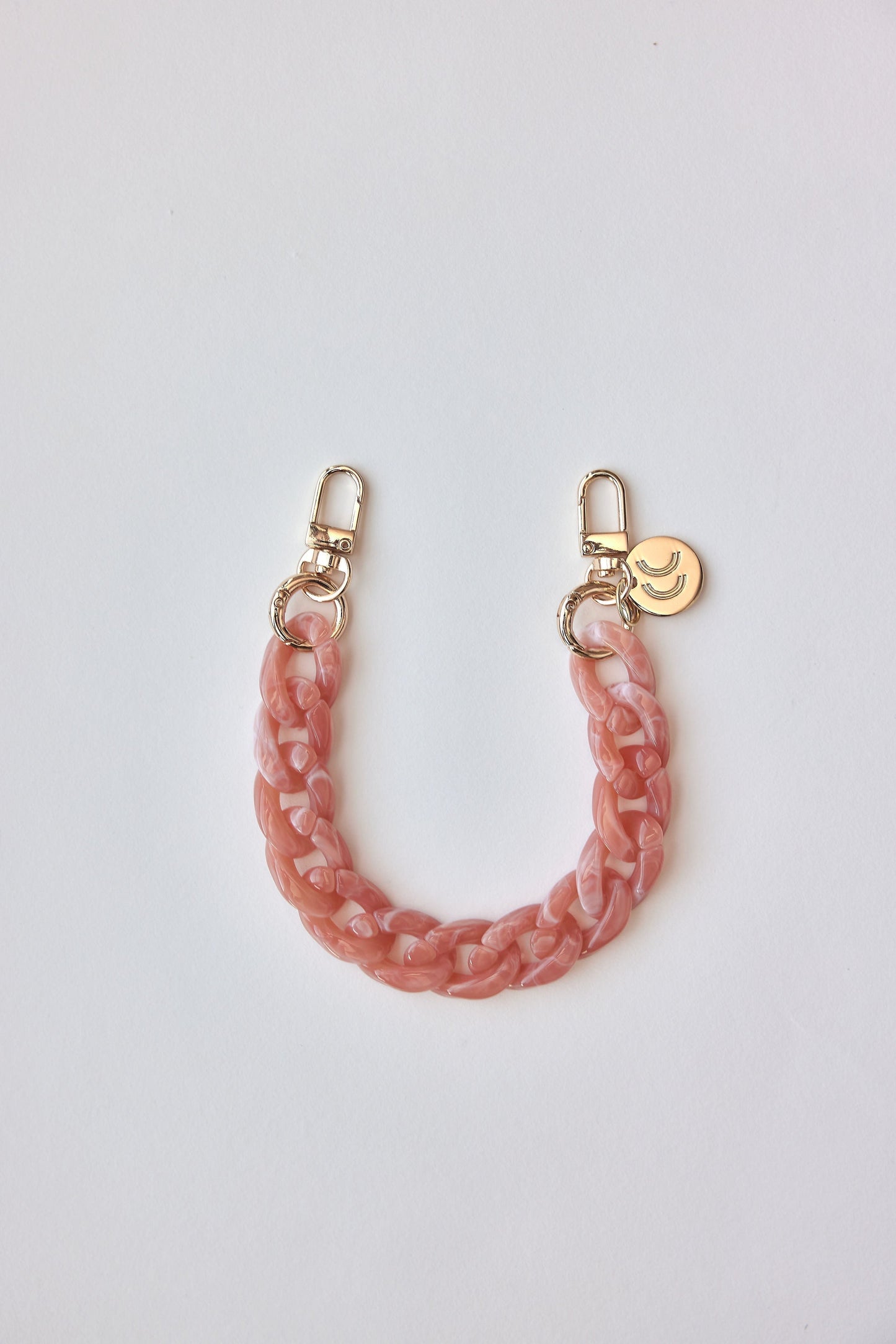 Detachable phone wristlets in pink with gold clasps.