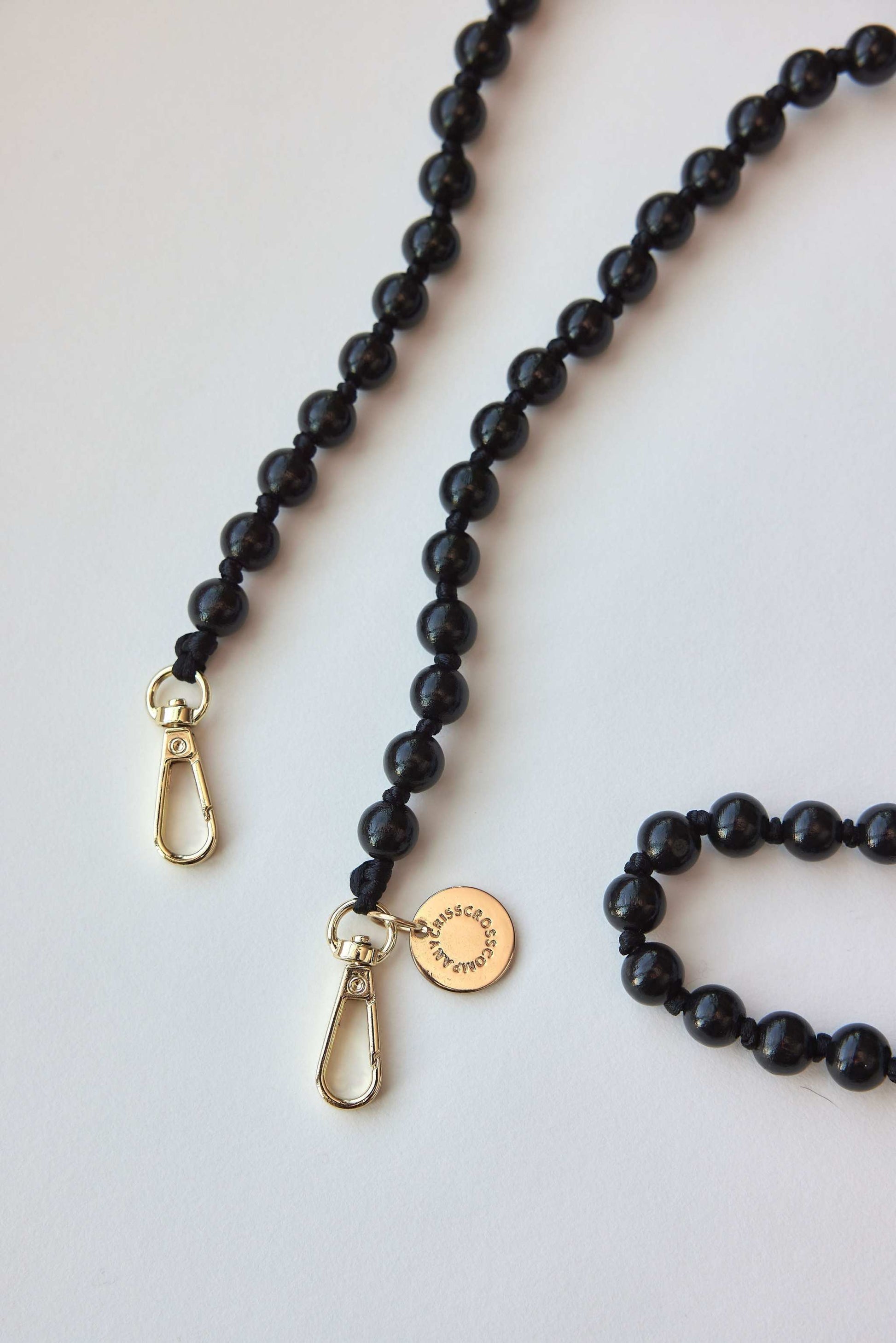 Detachable black beaded necklace with carabiners for easy attachment.