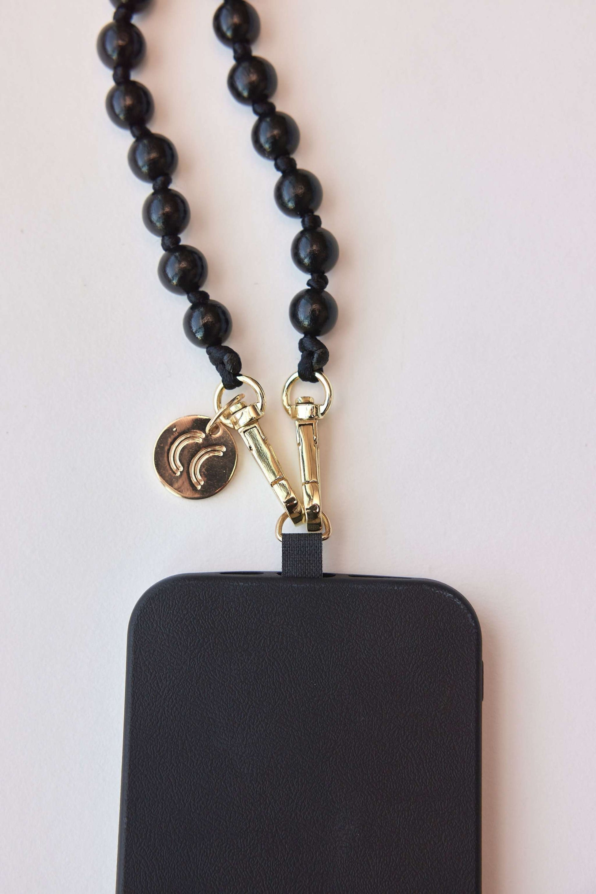 Detachable black beaded necklace with carabiners attached to a phone case.