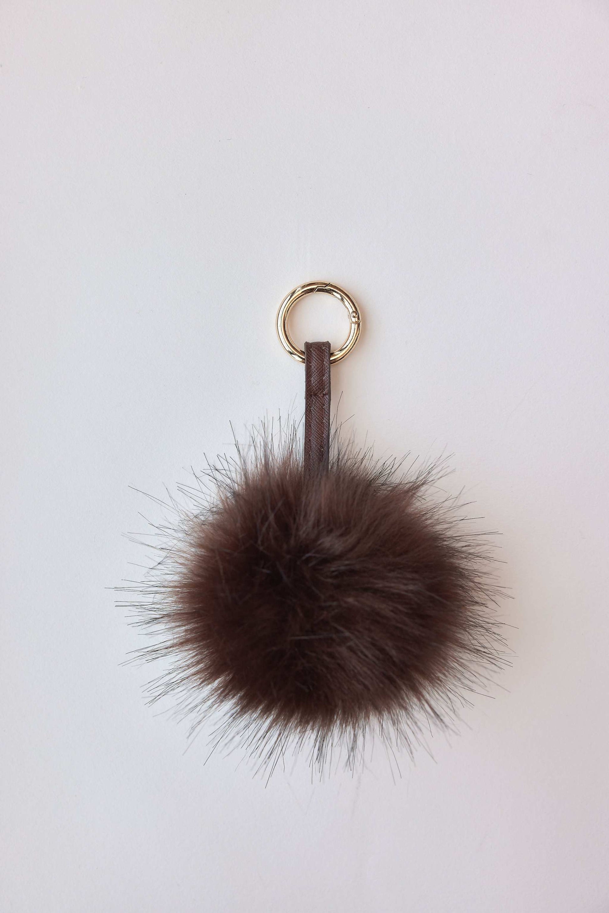 faux fur pom-pom accessory in brown with gold keychain attachment