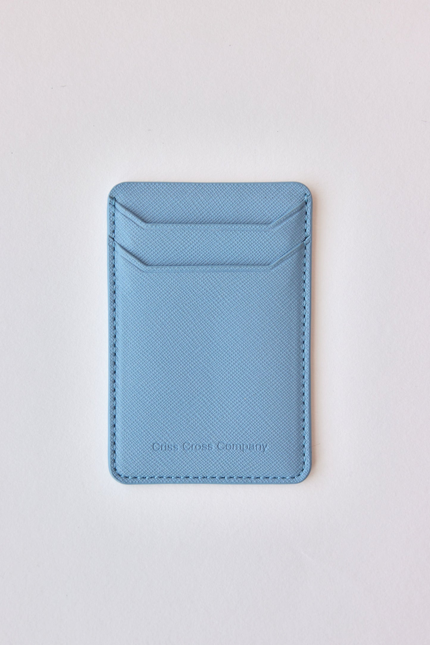 Sticky vegan leather phone wallet in light blue, with two card slots, designed for easy attachment to phone.