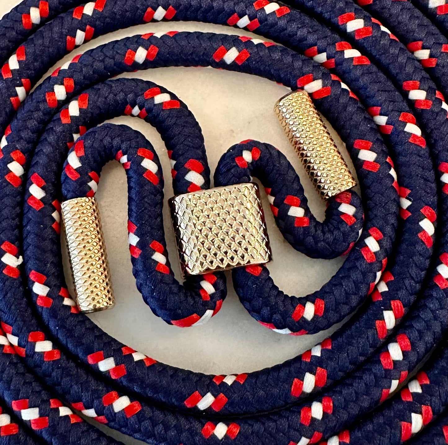 Phone case with attached stretchy strap featuring multi-color strap and gold metal accents.