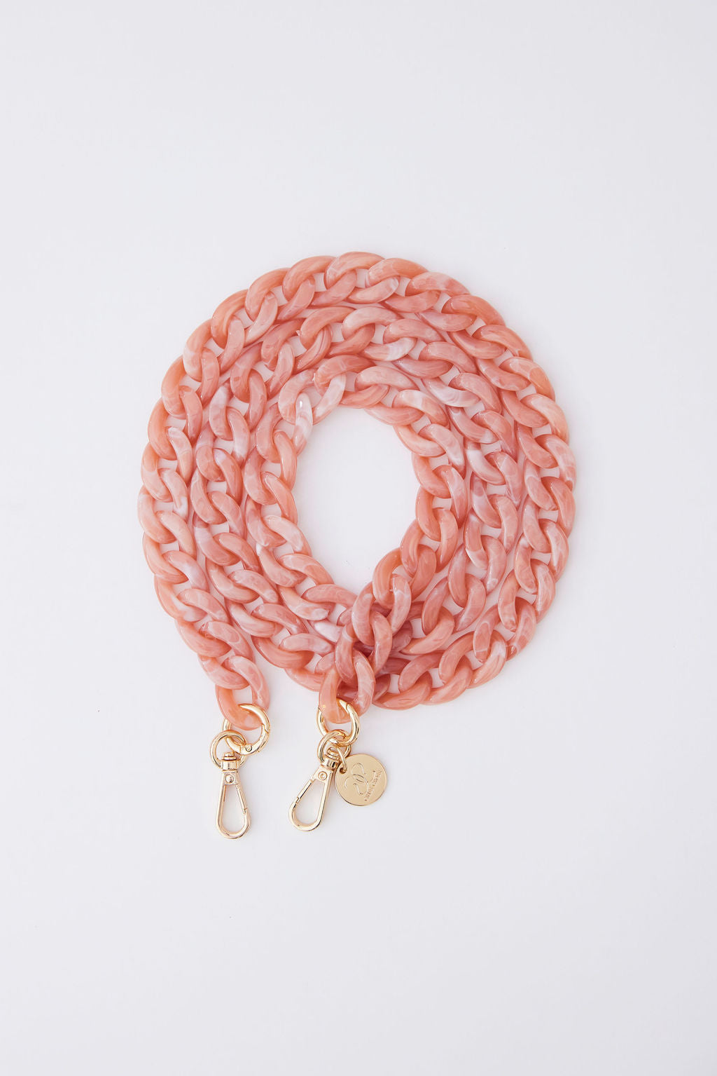 Detachable acrylic phone chain in blush color with gold rings and carabiners.