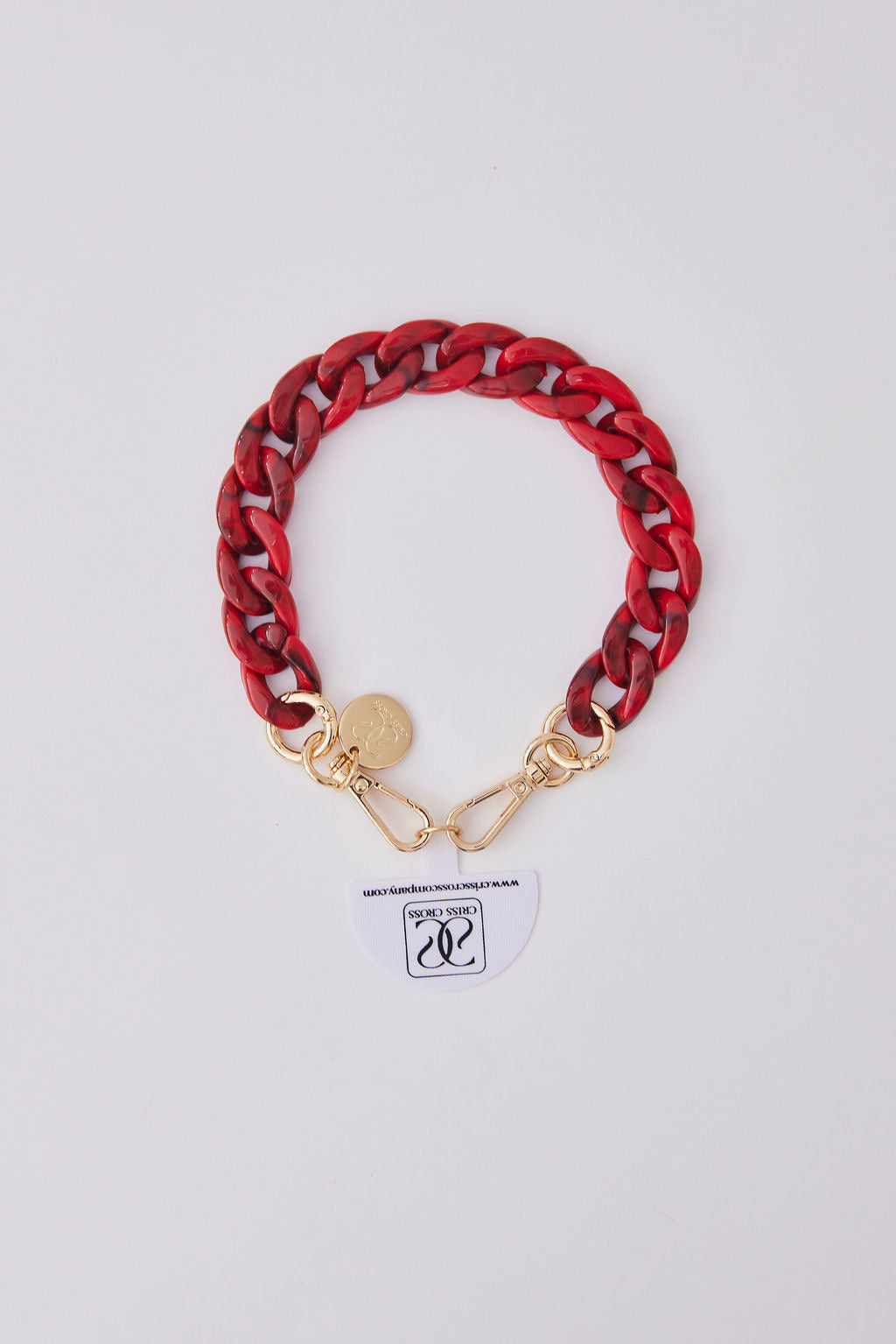 Red acrylic detachable phone wristlet with gold clasps and decorative charm on white background