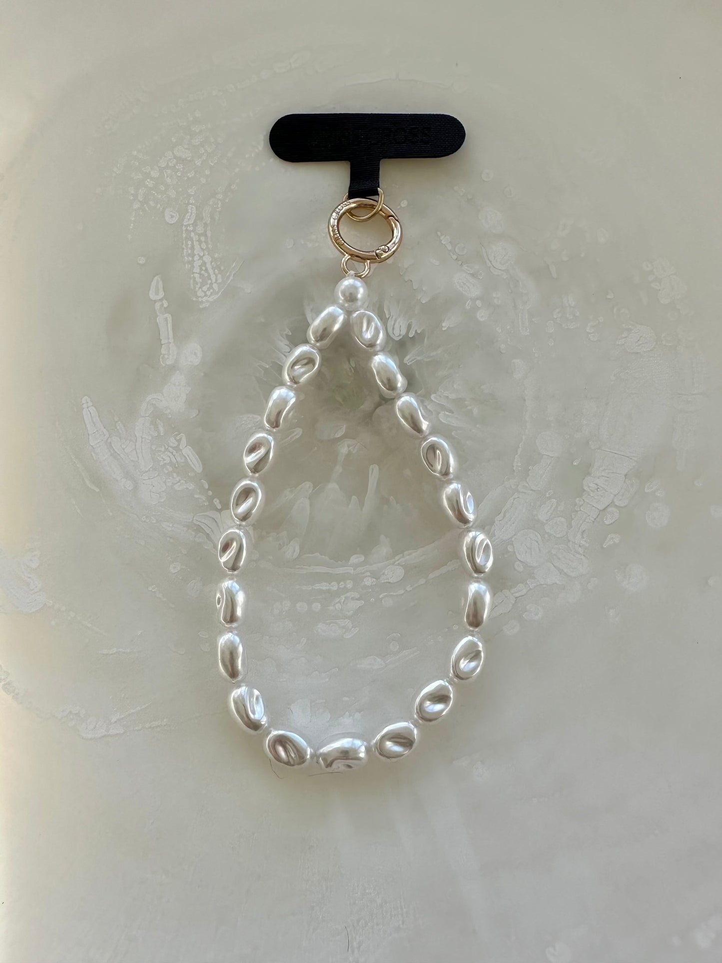 Pearl wristlet with universal phone patch adapter attachment for cases.