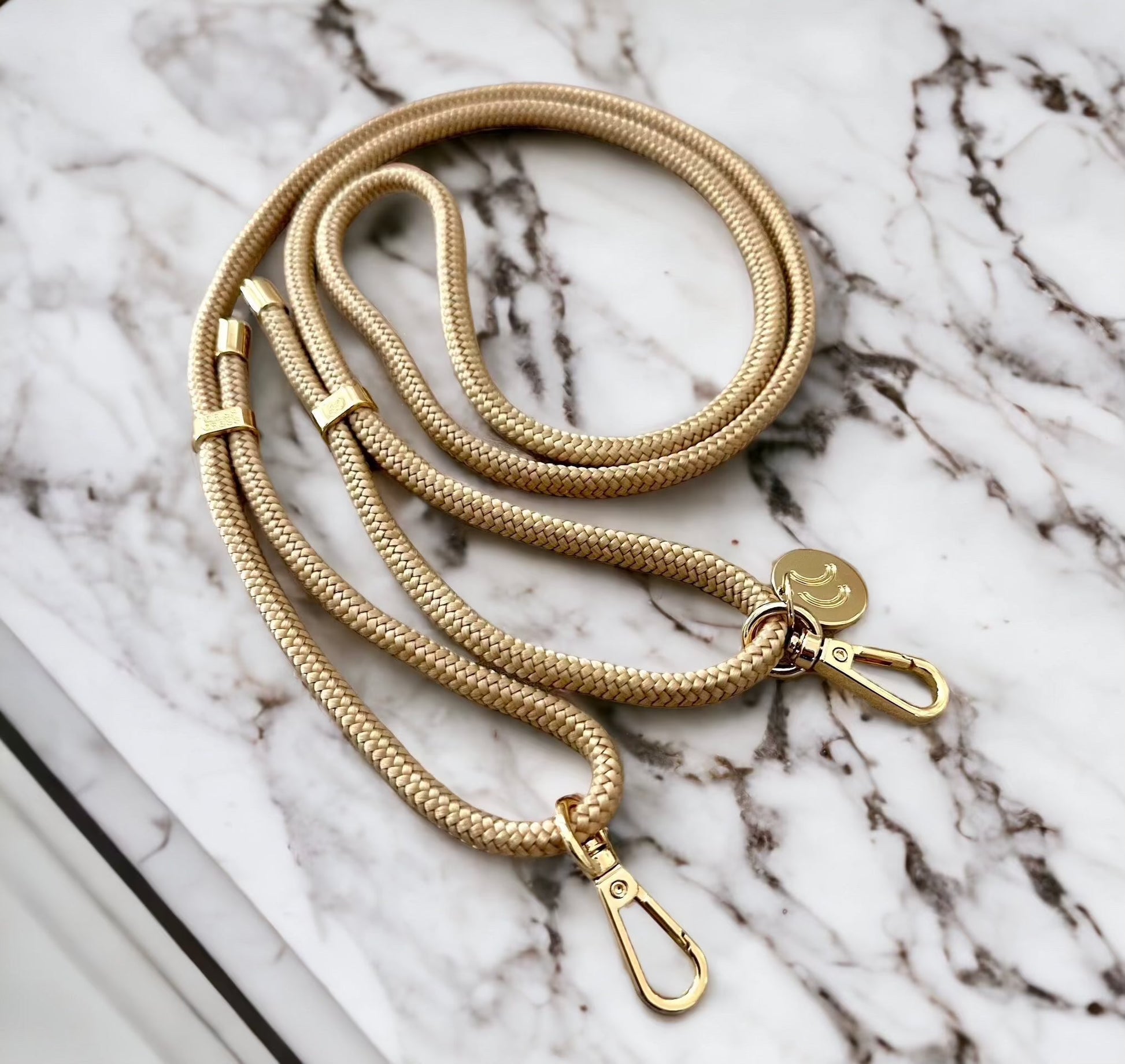 Detachable Poly Straps in sand color with carabiners on a marble surface.