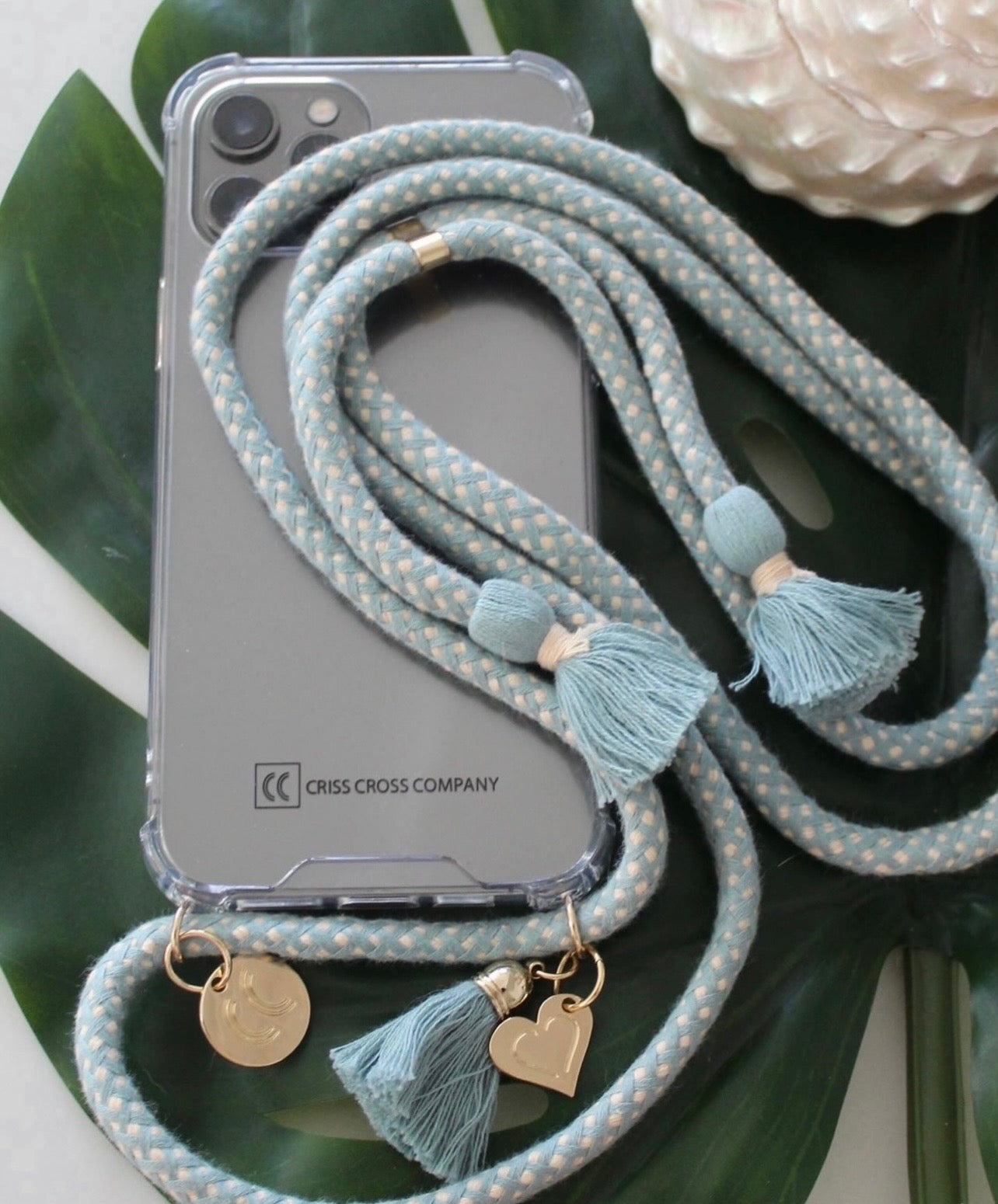 Phone case with attached cotton strap, tassels, and heart charm.