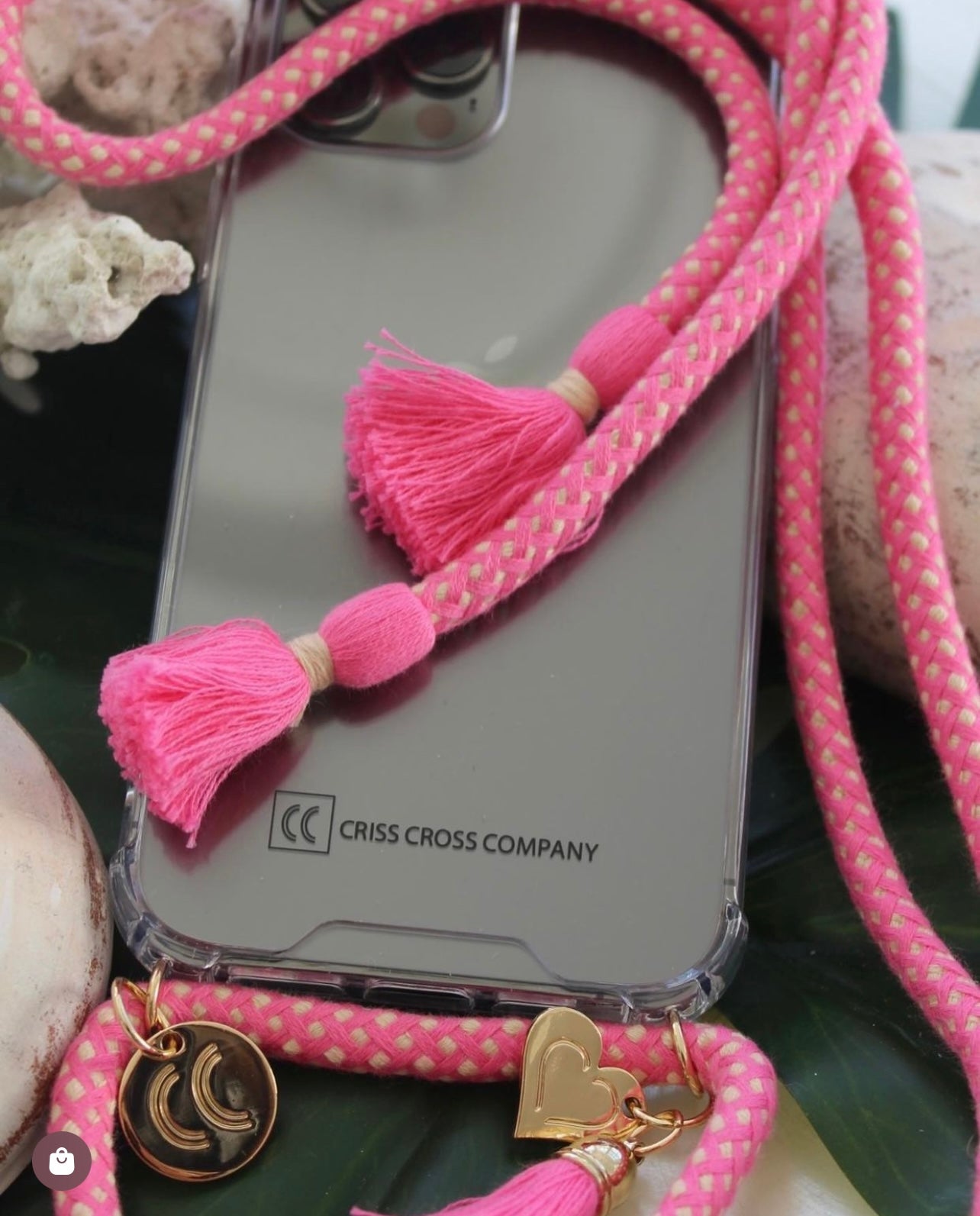 Phone case with attached cotton strap, tassels, and heart charm.