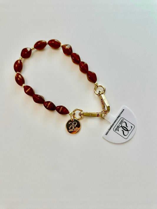 Brown beaded phone wristlet with acrylic beads and universal adapter attached to phone case