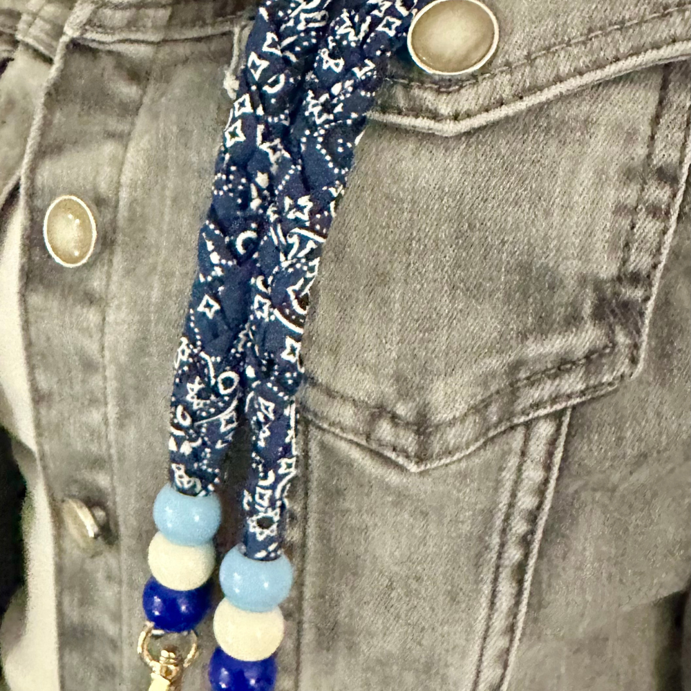 Blue bandana phone strap with beads attached to grey denim jacket